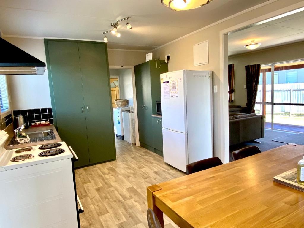 a kitchen with green cabinets and a white refrigerator at Comfortable & Close to Town in Twizel