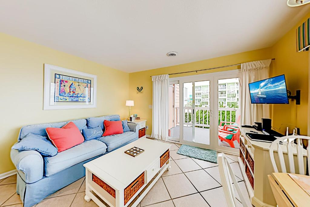 een woonkamer met een blauwe bank en een tafel bij Cozy Carolina Beach Condo in Carolina Beach