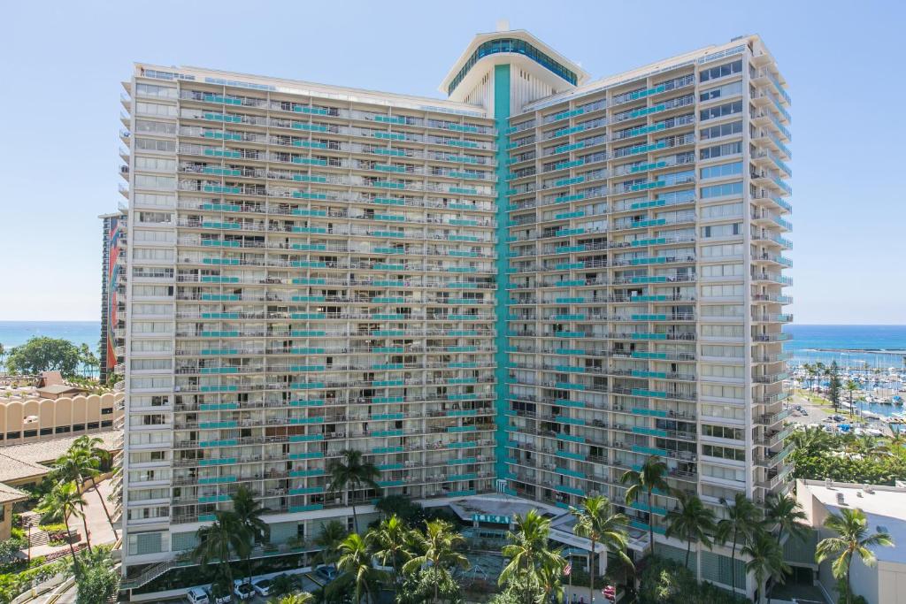 a tall building with palm trees in front of the ocean at Ilikai Tower 1228 Lagoon View 1BR in Honolulu