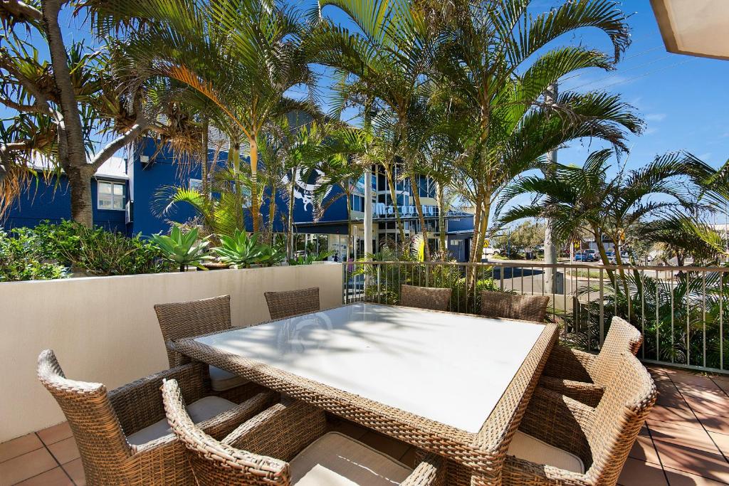einen Tisch und Stühle auf einem Balkon mit Palmen in der Unterkunft Surfcomber on the Beach in Maroochydore