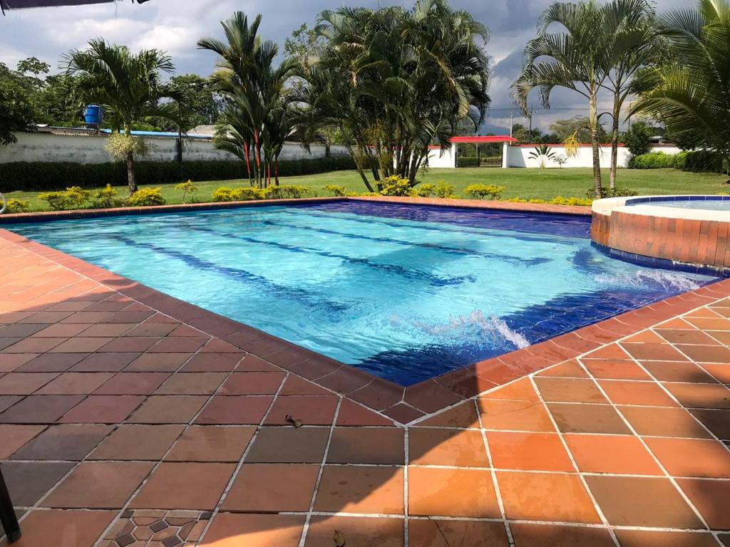 a large swimming pool with a tile floor and anergynergynergynergyploadpload at Finca Turística Villa Natasha - Casa Campestre y Cabañas Villavicencio in Villavicencio