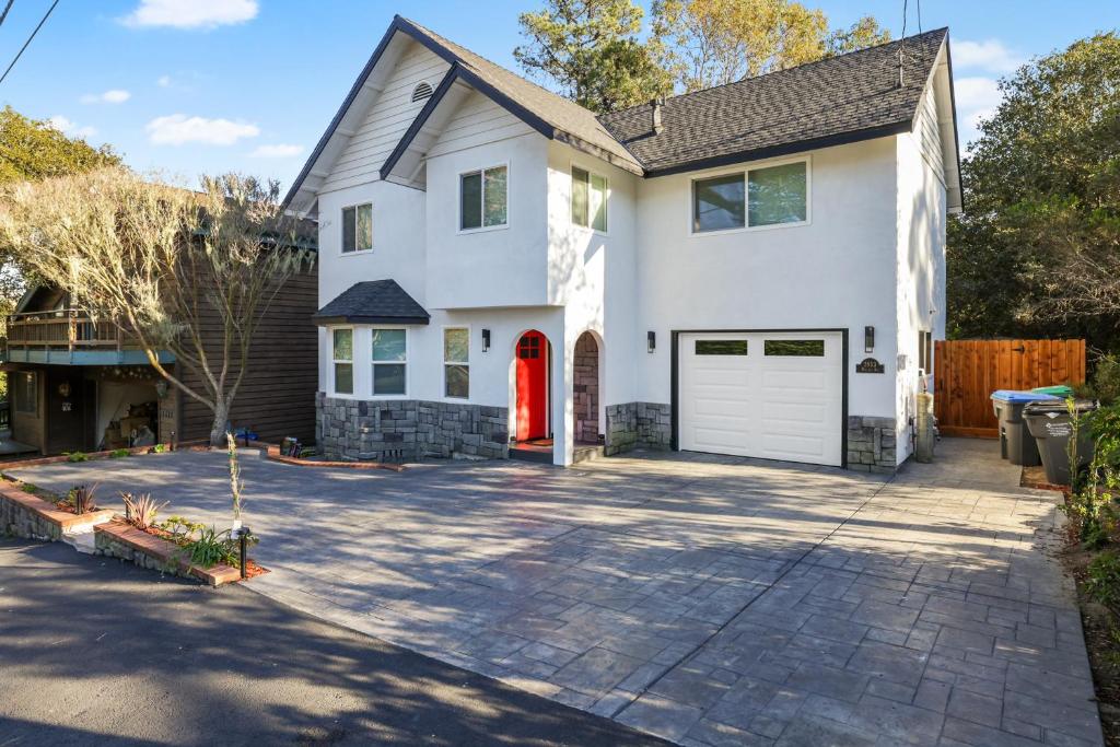 a white house with a red door and a driveway at Wanderlust Cambria Seaside Village in Cambria