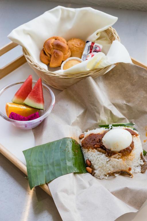 A mixed breakfast tray with fruit, pastries, and a rice dish served on banana leaf.