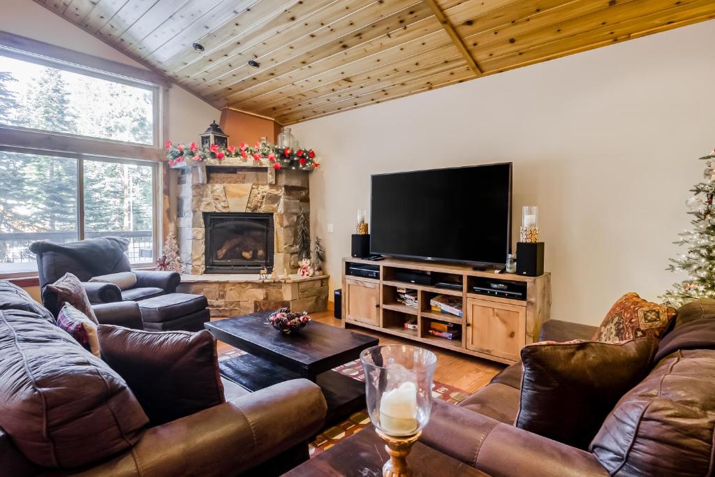 sala de estar con muebles de cuero y TV de pantalla plana en The Alpine Divine, en Truckee