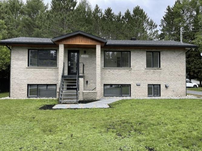 a brick house with a porch and a grass yard at Complexe LIVTremblant by Gestion ELITE - LIV6 in Mont-Tremblant