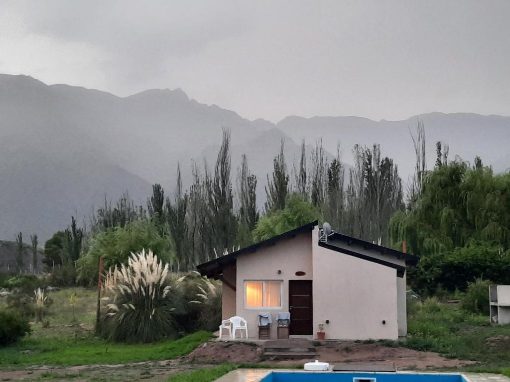 una pequeña casa blanca con montañas en el fondo en Starry Lodge en Luján de Cuyo