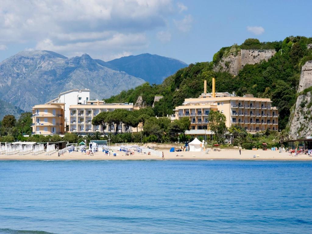 una spiaggia con edifici e persone sulla spiaggia di Hotel Serapo a Gaeta