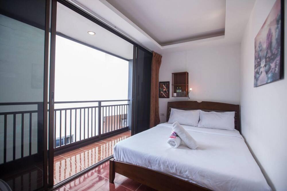 a bedroom with a bed and a large window at Kamala bay inn in Kamala Beach