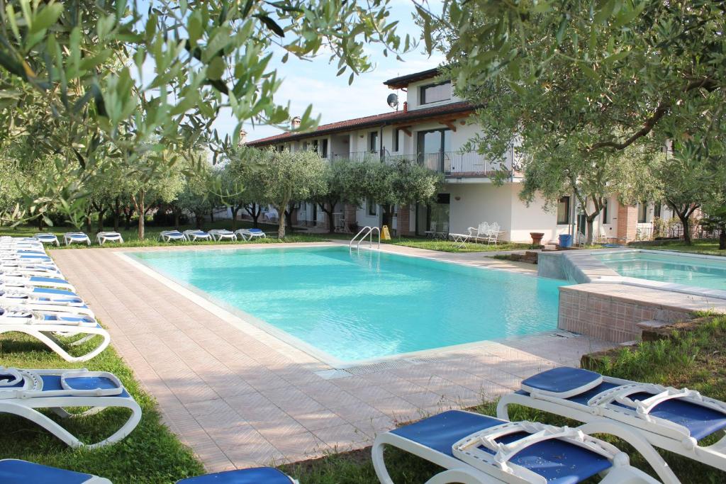 a swimming pool with lounge chairs and a house at Residence Ulivi in Cavaion Veronese