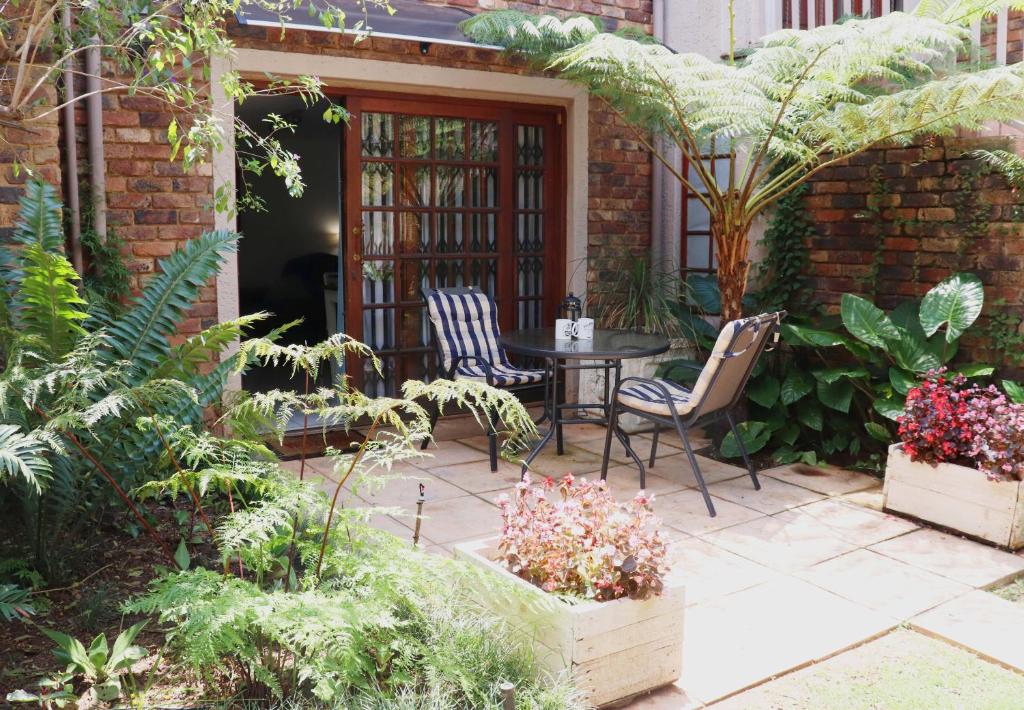 a patio with a table and chairs and plants at Green Scape Flatlet in Pretoria