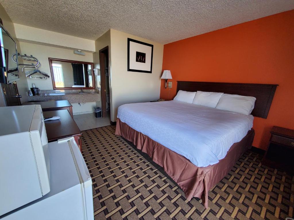 a large bed in a hotel room with an orange wall at Relax Inn Henryetta in Henryetta