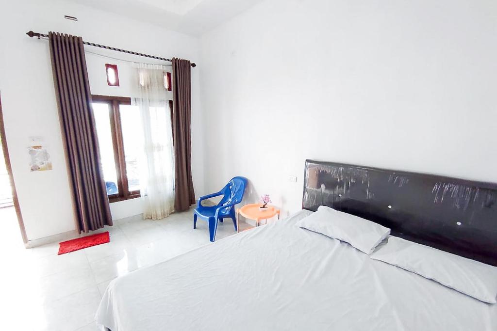 een slaapkamer met een bed en een blauwe stoel bij Sapu Nyapah Losmen Syariah Tanjung Setia in Biha