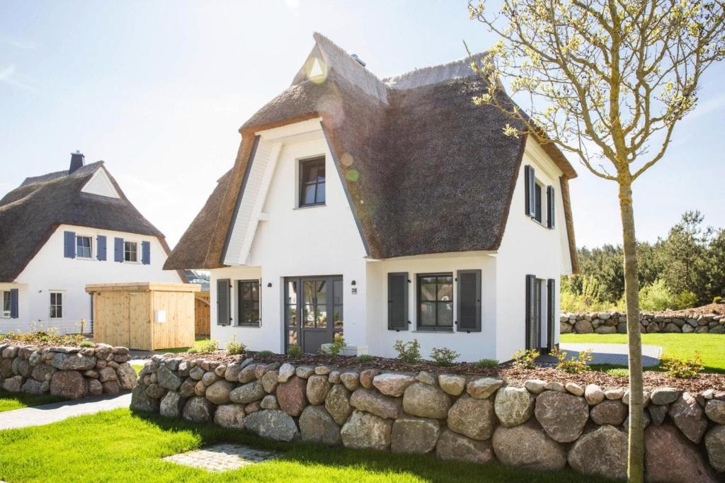 a white house with a stone wall at Holiday house, Fuhlendorf in Fuhlendorf