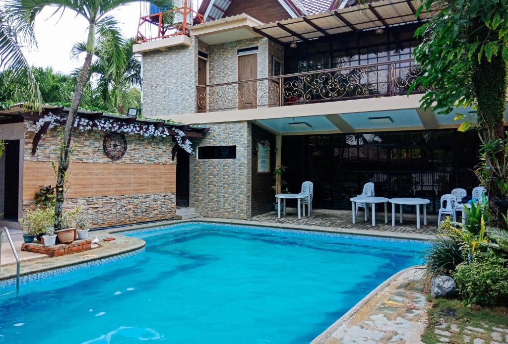 una piscina frente a una casa con patio en Villa Asuncion Country Inn and Resort Iloilo by RedDoorz en Iloilo