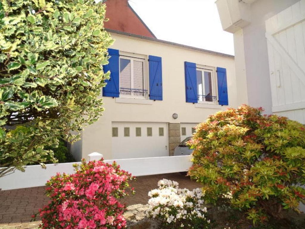 a white house with blue shutters and flowers at Apartment, Quimper in Quimper