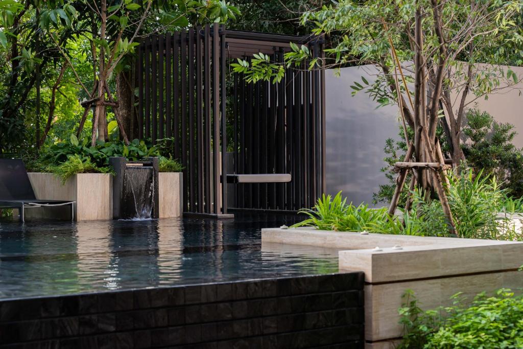 A landscaped pool framed by trees, planters and a dark garden screen.