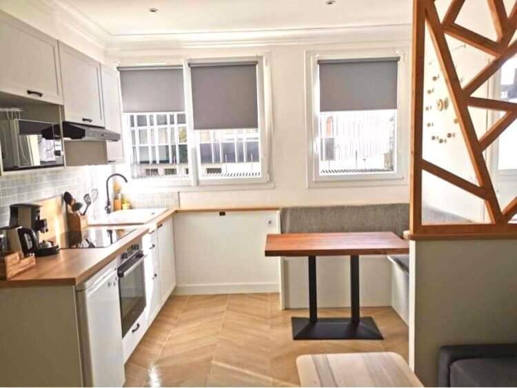 Bel appartement rénové, centre de Vannes في فان: مطبخ بدولاب بيضاء وطاولة خشبية