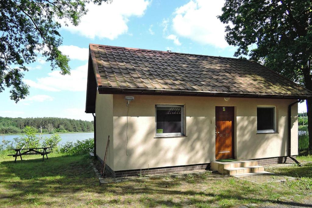 a small white house next to a lake at Holiday House in Szczecin at the lake with parking space for 4 persons in Szczecin