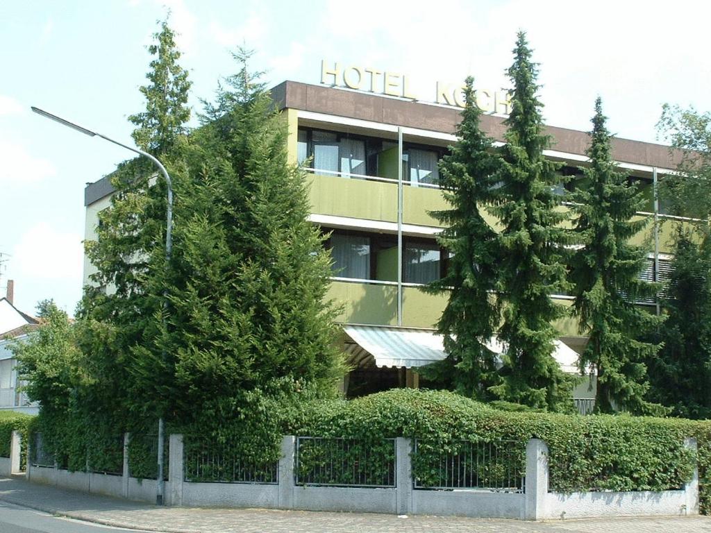 オーベルツハウゼンにあるHotel Koch Maingauの目の前に木々が生い茂るホテルの建物