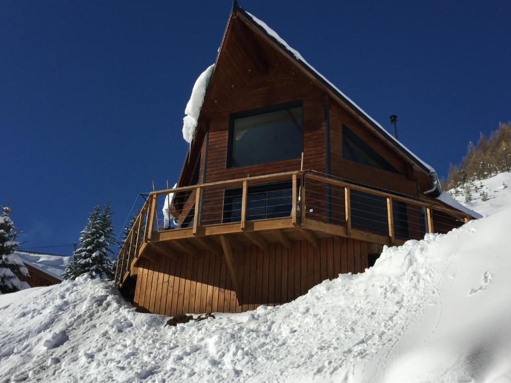 Cabaña de madera en una ladera cubierta de nieve en CHALET TRIPTYQUE en Orcières
