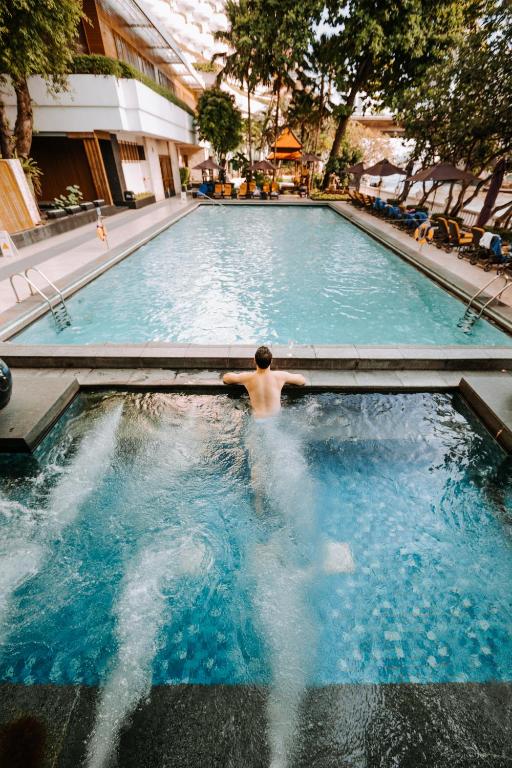 A long outdoor pool extends through a landscaped courtyard, with a bubbling foreground spa pool.
