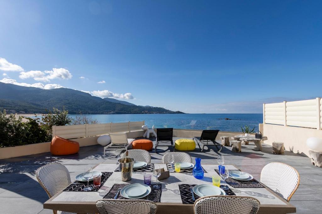 um pátio com uma mesa e cadeiras e vista para o oceano em La Maison sur la Plage em Calcatoggio