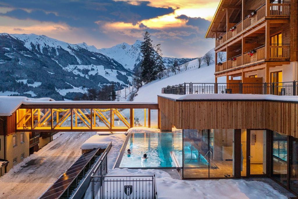 a hotel with a swimming pool in the snow at Berghotel Hauserbauer in Dorfgastein