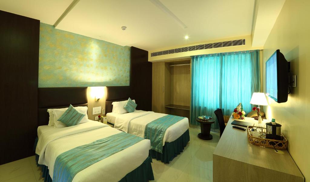 a hotel room with two beds and a television at Renest Tirupati in Tirupati