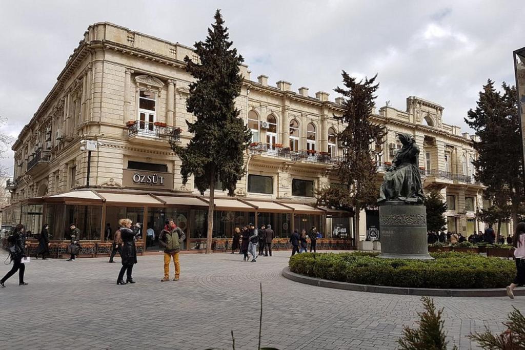 un grand bâtiment avec des personnes qui marchent devant lui dans l'établissement Bristol Hotel, à Baku