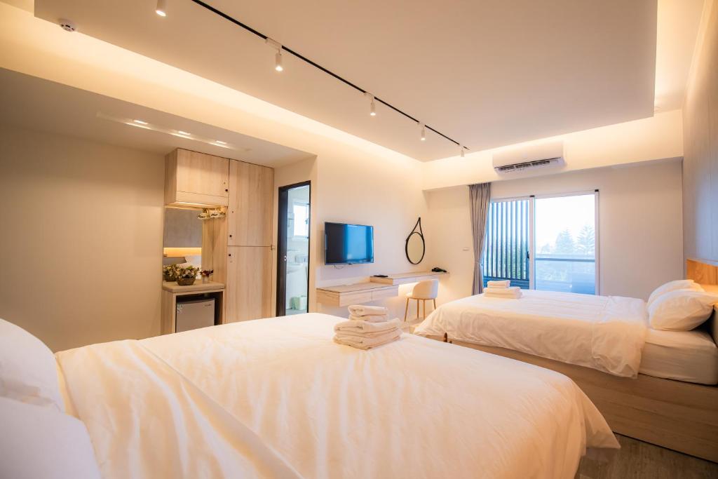 um quarto de hotel com duas camas e uma casa de banho em 澎湖綠果昔民宿-可包棟 em Magong