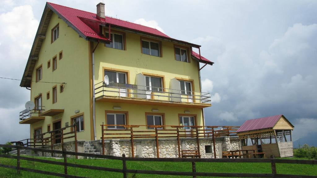 ein großes gelbes Haus mit rotem Dach in der Unterkunft Pensiunea Pui de Urs Sirnea in Fundata