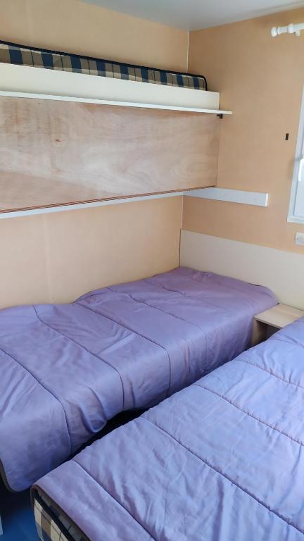 2 camas en una habitación pequeña con sábanas moradas en mobil-home du lac de Foix en Foix