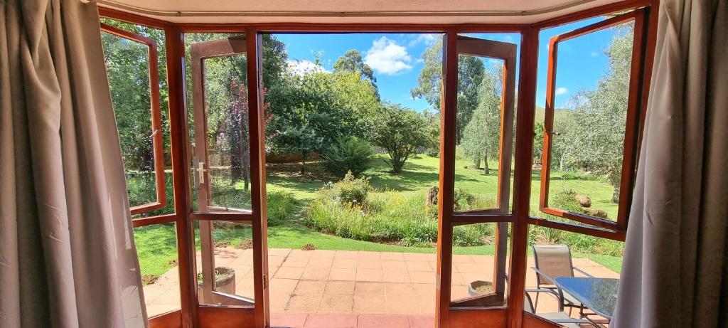 an open window with a view of a garden at DullVino Cottage @ Critchley in Dullstroom