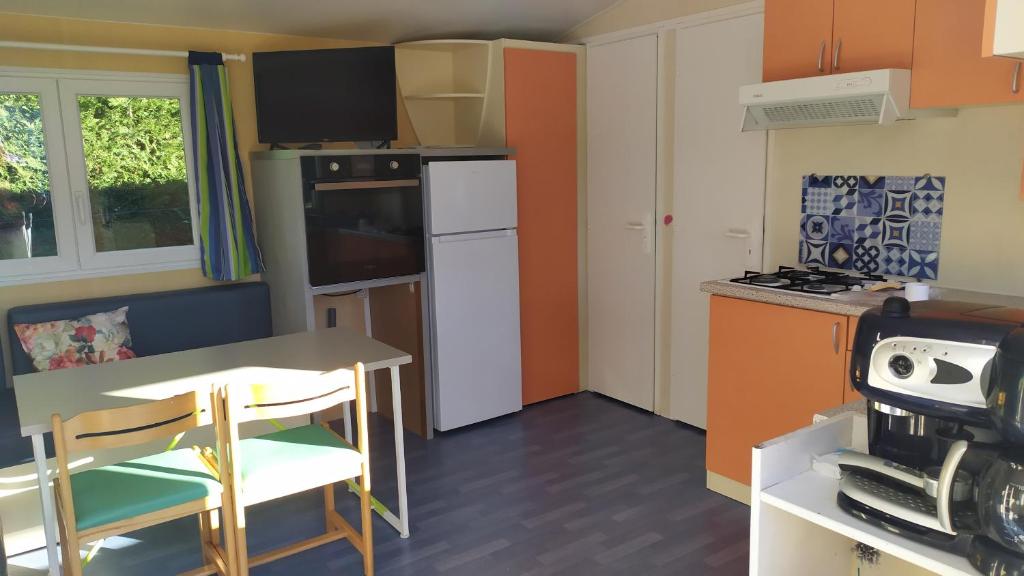 a small kitchen with a table and a refrigerator at mobil-home du lac de Foix in Foix