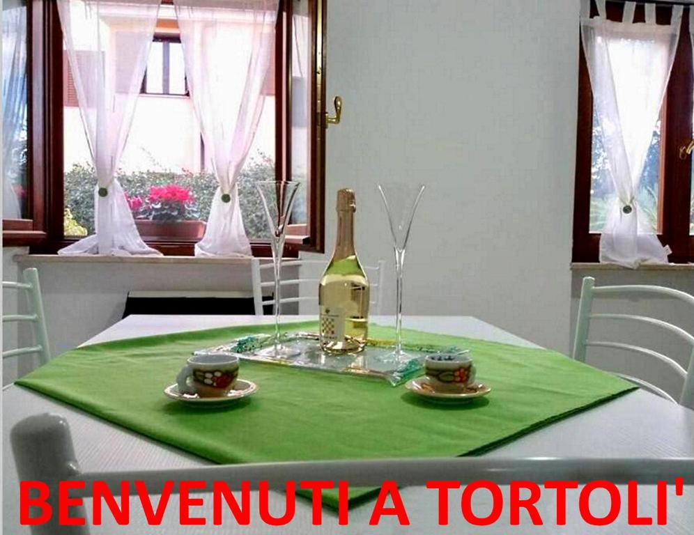 una botella de vino sentada en una mesa con dos tazas en Appartamento La Rocca, en Tortolì