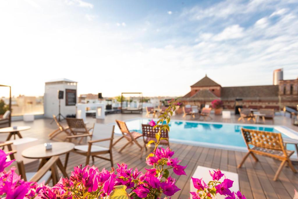 d'une terrasse avec des tables, des chaises et des fleurs violettes. dans l'établissement Zenit Sevilla, à Séville