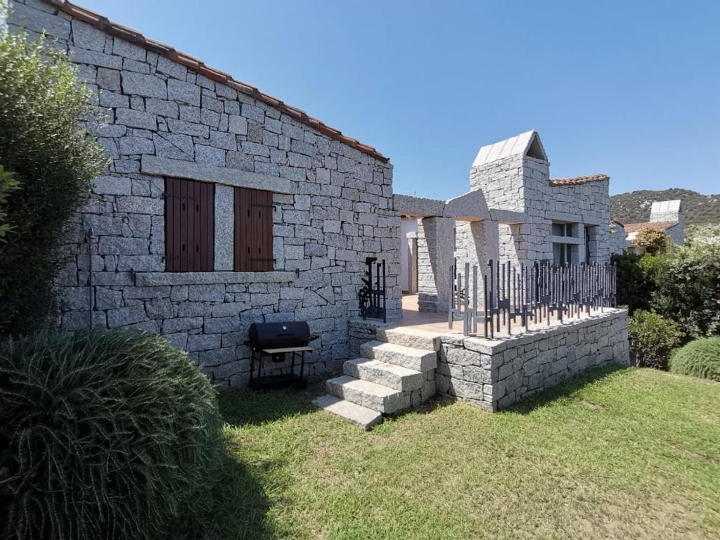 una casa de piedra con una valla y un patio en villa 27, en Castiadas