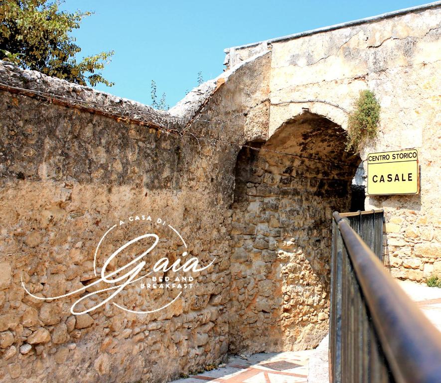 eine alte Steinmauer mit einem Schild drauf in der Unterkunft A Casa Di Gaia Bed and Breakfast in Vico del Gargano