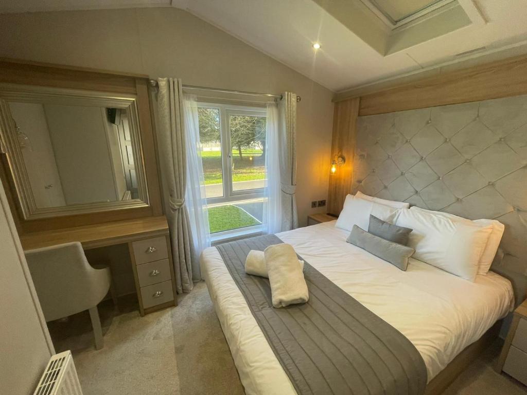 a bedroom with a large white bed with a window at Brians Lodge with Hot Tub in Pocklington