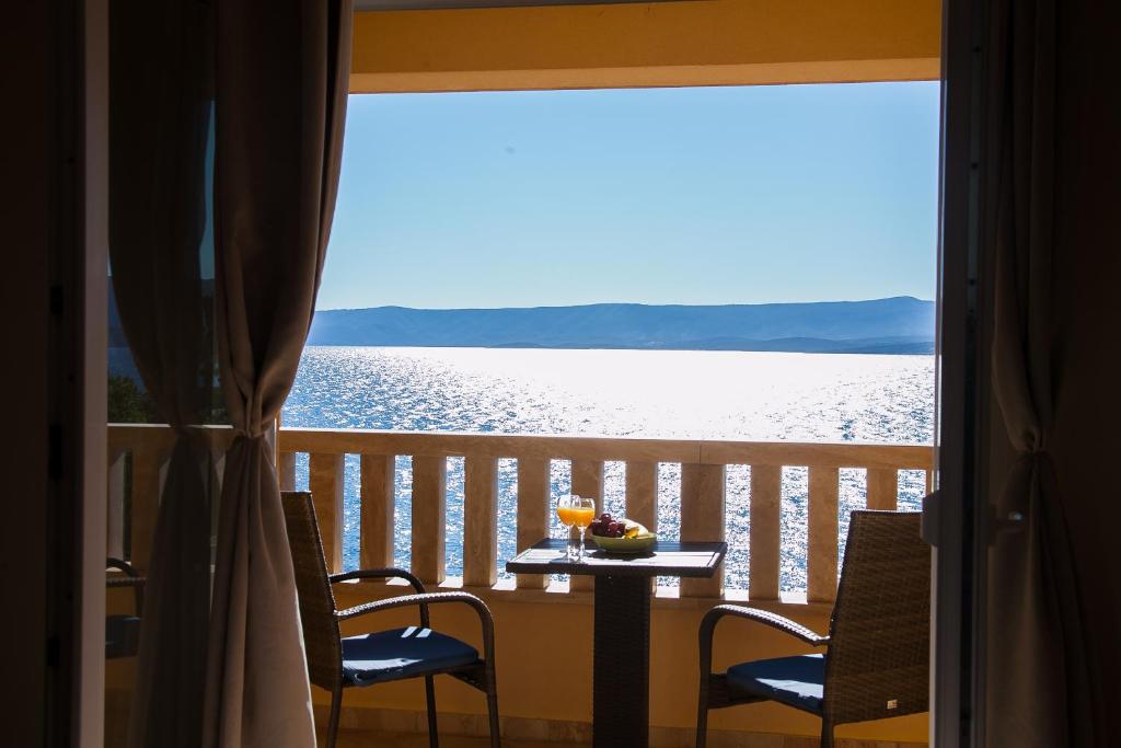 un tavolo e sedie su un balcone con vista sull'acqua di Hotel Villa Džamonja a Bol