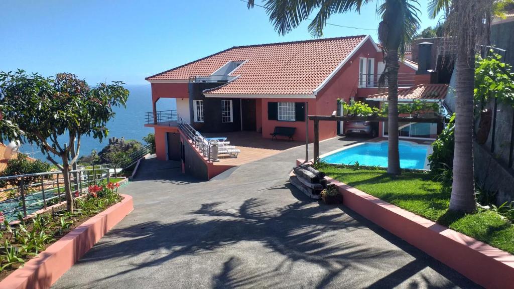 a house with a swimming pool next to the ocean at Casa das Palmeiras in Calheta