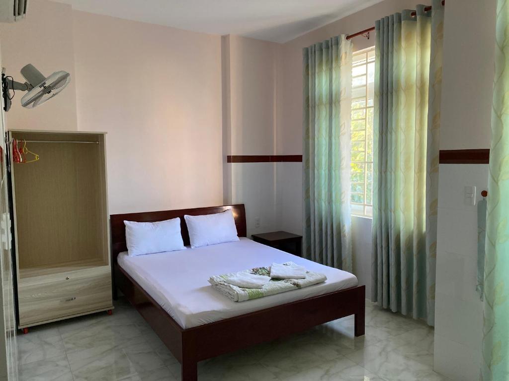 sypialnia z łóżkiem z białą pościelą i oknem w obiekcie Hoang Minh 846 Hostel w mieście Vung Tau