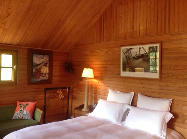 1 dormitorio con 1 cama en una pared de madera en Domaine de Thyllères,Chalets Voilier, en Beaufour