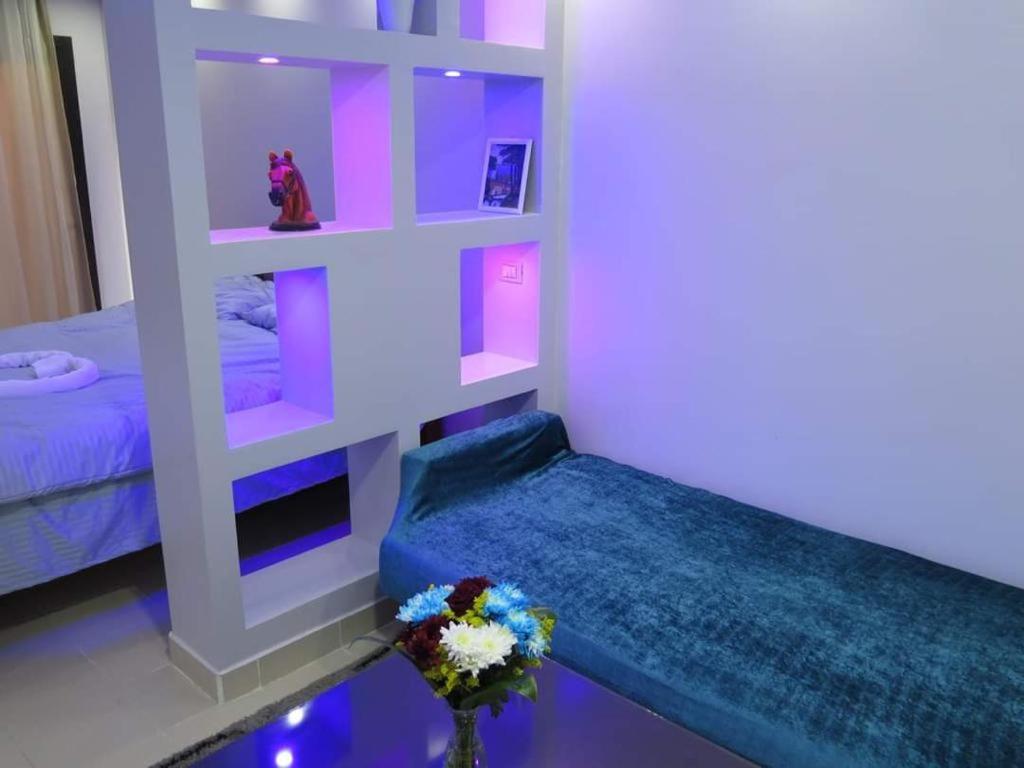 a room with a bed and a shelf with flowers at The view studio in Hurghada