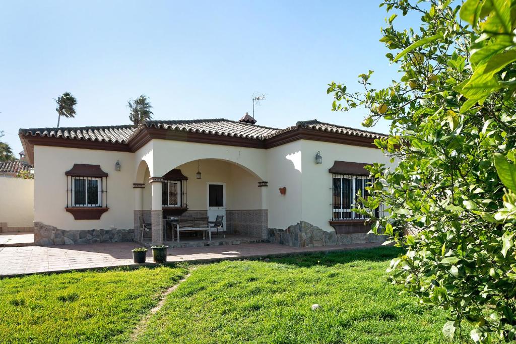 a house with a green lawn in front of it at La Flor in Chiclana de la Frontera