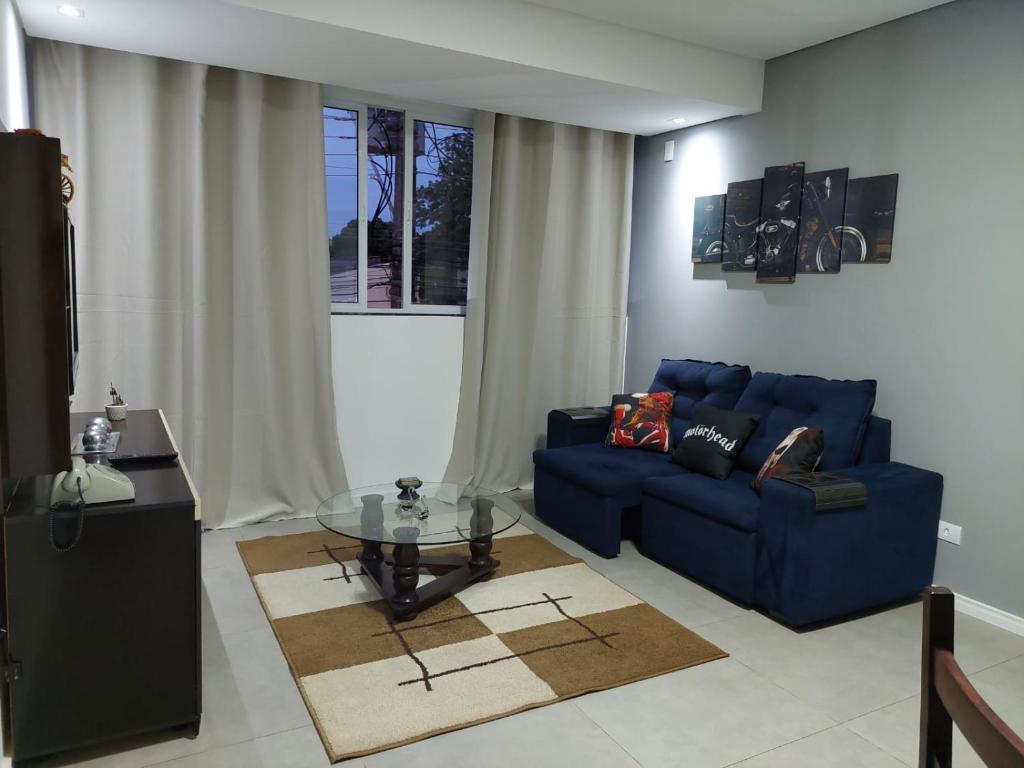 uma sala de estar com um sofá azul e uma mesa de vidro em Ótimo apartamento sobreloja com wifi e estacionamento incluso em Maringá