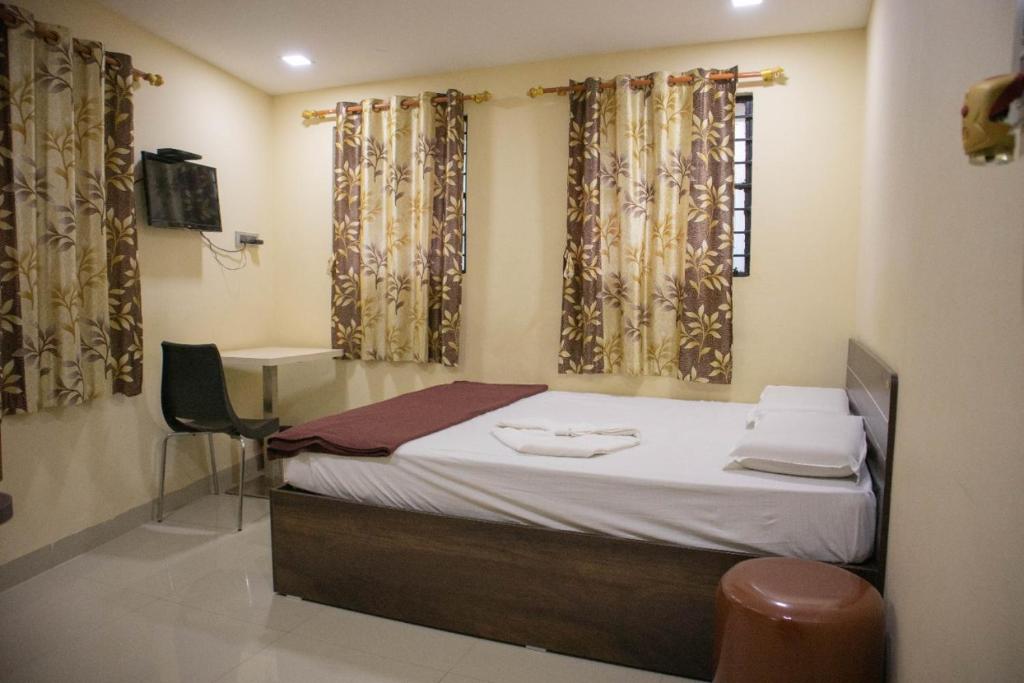 Cette chambre comprend un lit, un bureau et des rideaux. dans l'établissement Shri Vasant Lodge, à Hubli