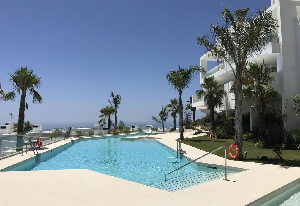 a swimming pool in front of a building with palm trees at Luxury apt in the hills of Marbella in Ojén