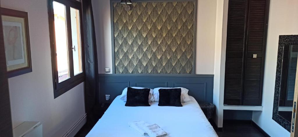 een slaapkamer met een wit bed en 2 zwarte kussens bij Hotel de la Place in Loyettes