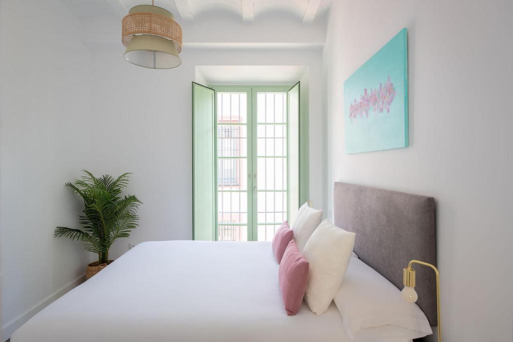 a white bedroom with a large bed and a window at Hommyhome Teodosio in Seville